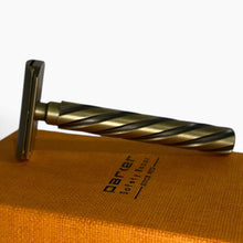 Load image into Gallery viewer, A vintage-style safety razor with a twisted handle and dark metal head, resting on an orange textured box printed with the brand name 'parer'.