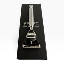 Load image into Gallery viewer, A silver safety razor with a textured handle and black guard, resting on top of its black textured presentation box. The box features the brand name 'Parker' and the words 'Safety Razor'.
