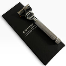 Load image into Gallery viewer, A silver metal safety razor with a knurled handle, resting on top of a black textured zippered case. The case features the white printed brand name 'BARKER' and the text 'Safety Razor' and 'SINCE 1972'.
