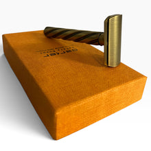 Load image into Gallery viewer, A brass safety razor with a twisted handle rests on top of a textured orange presentation box. The box features the brand name 'PARKER' printed in black.
