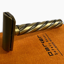 Load image into Gallery viewer, A vintage-style safety razor with a brushed gold and dark bronze finish, resting on an orange textured towel printed with the brand name 'Jazzy'.
